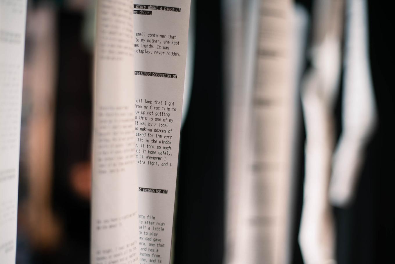 Forest archive, with many thermal papers hanging down. Words and stories are visible but not readable.